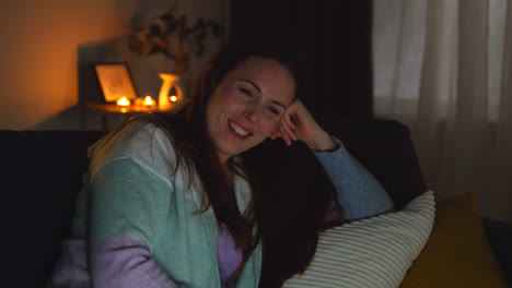 Smiling-Woman-Sitting-On-Sofa-At-Home-At-Night-Streaming-Or-Watching-Movie-Or-Show-On-Laptop-3